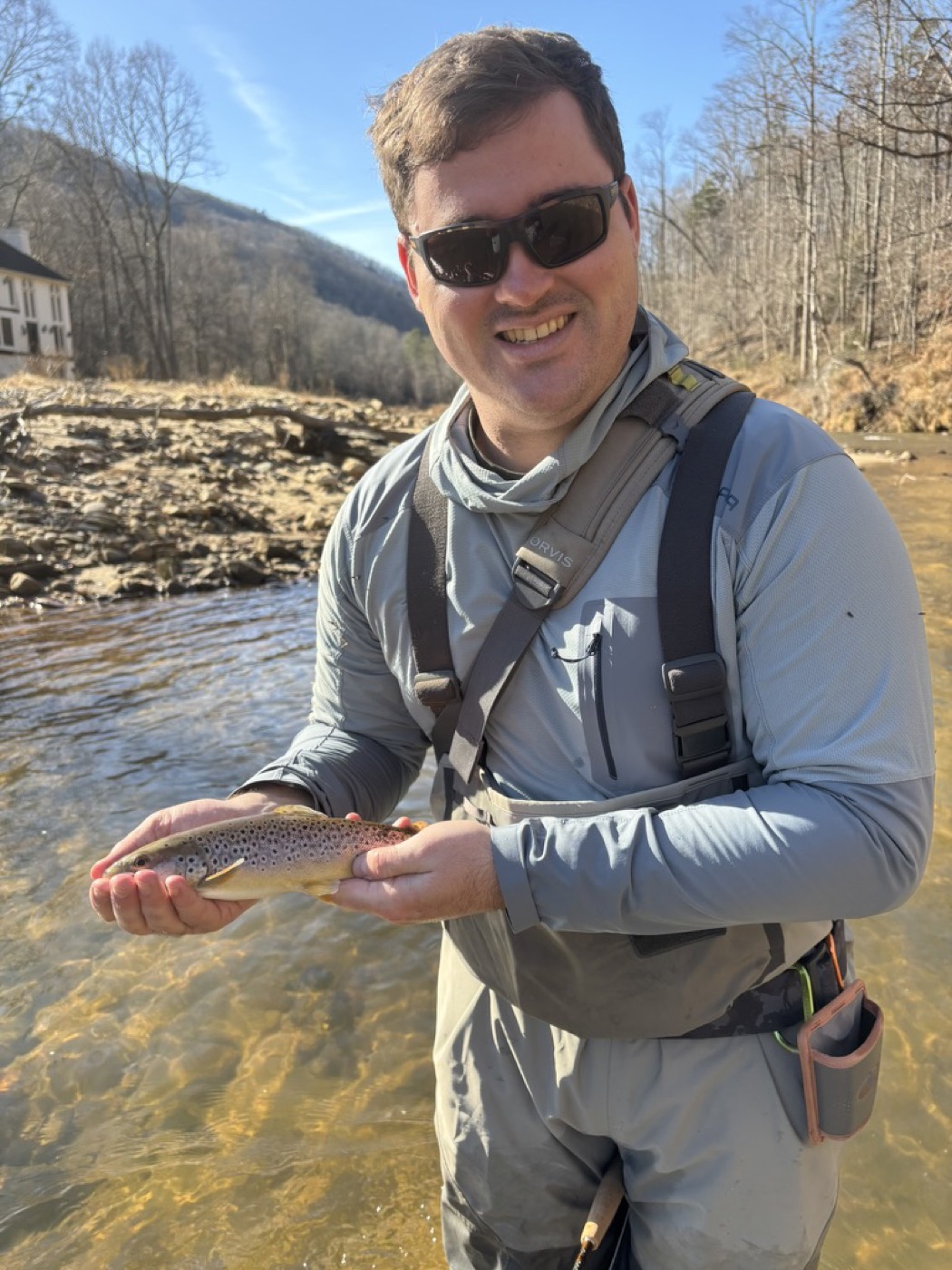 Angler holding a brown trout on a sunny river